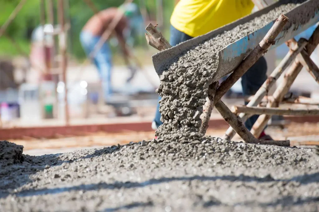 Close-up of fresh concrete mix being poured from chute by concrete contractors in Olathe KS